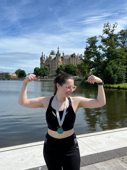 Runner wearing the black Tigers Eye bra posing with half-marathon medal in Berlin.